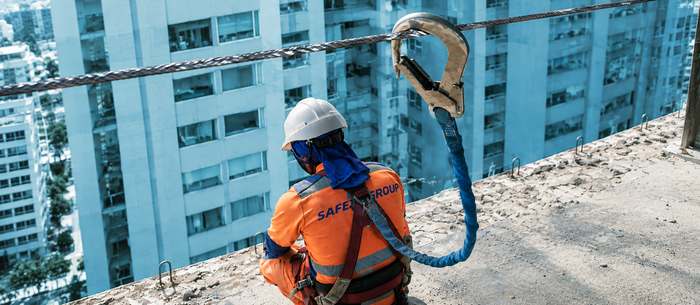 Trabajador conectado a línea de vida en fachada de edificio urbano
